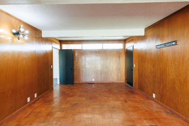 unfurnished room with beamed ceiling, parquet flooring, a textured ceiling, and wood walls