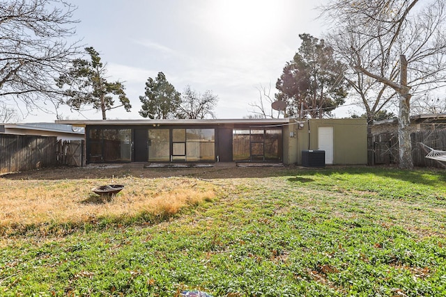 back of house featuring a fire pit, central air condition unit, and a lawn