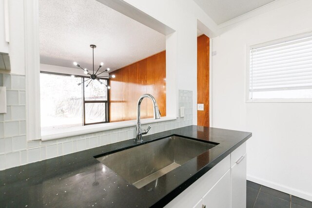 kitchen featuring sink, tasteful backsplash, an inviting chandelier, hanging light fixtures, and a textured ceiling