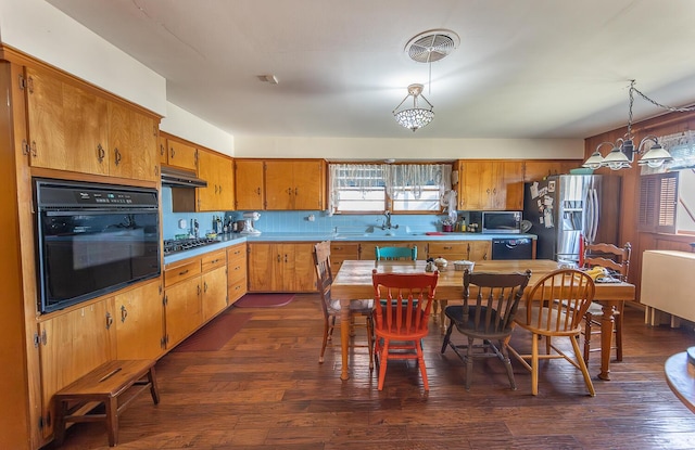 kitchen with under cabinet range hood, decorative light fixtures, brown cabinetry, and black appliances