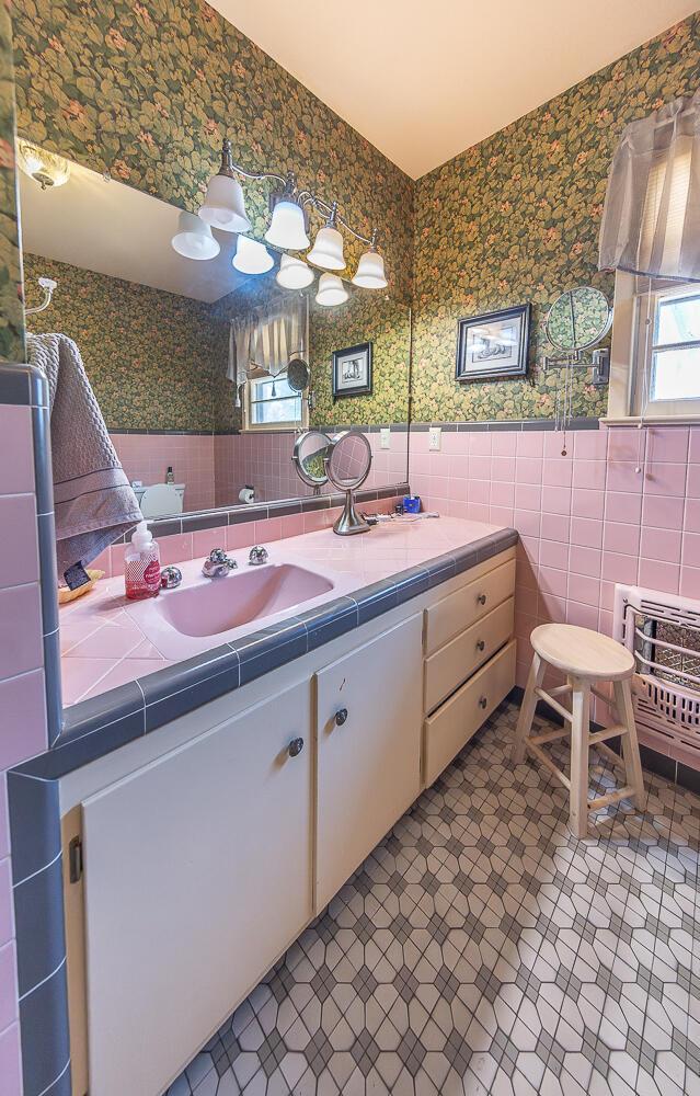 bathroom featuring wallpapered walls, tile walls, heating unit, and a wainscoted wall