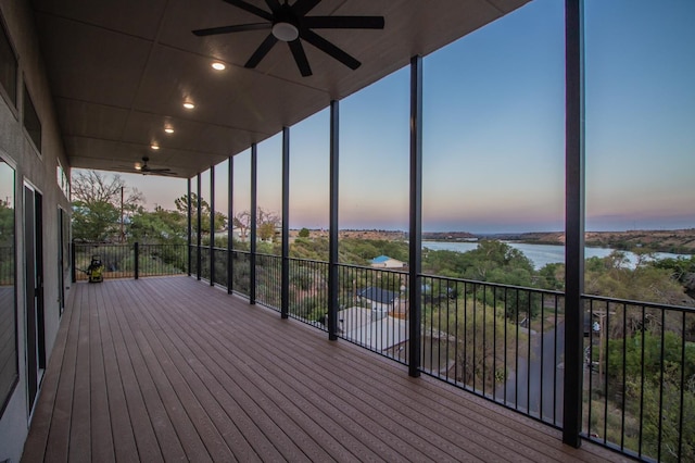 deck at dusk with ceiling fan and a water view