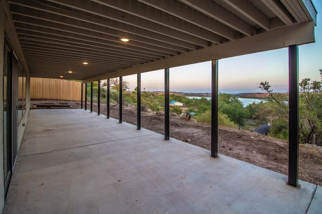 patio terrace at dusk featuring a water view