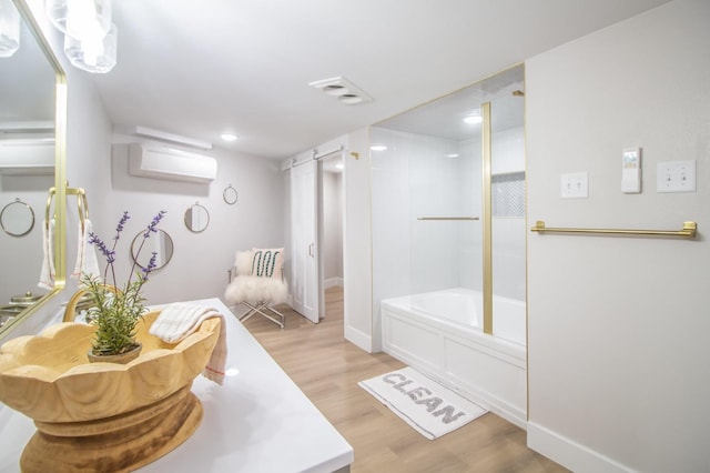 bathroom featuring vanity, shower / bath combination with glass door, wood-type flooring, and a wall unit AC