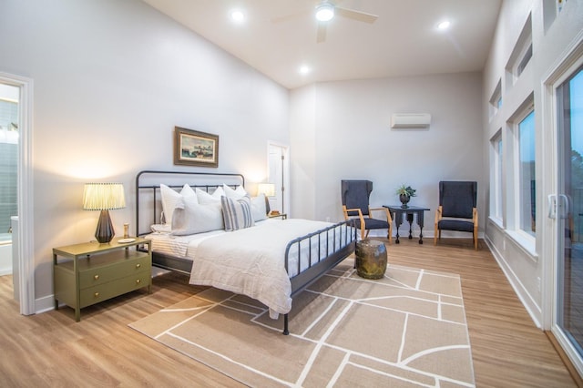 bedroom featuring an AC wall unit, a towering ceiling, hardwood / wood-style floors, and ceiling fan