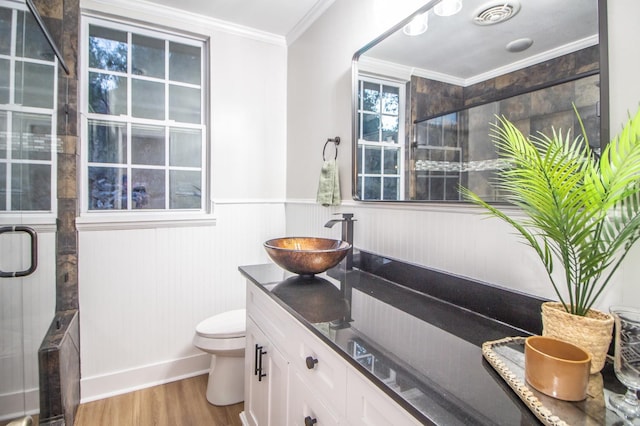 bathroom with hardwood / wood-style floors, a shower with shower door, ornamental molding, vanity, and toilet