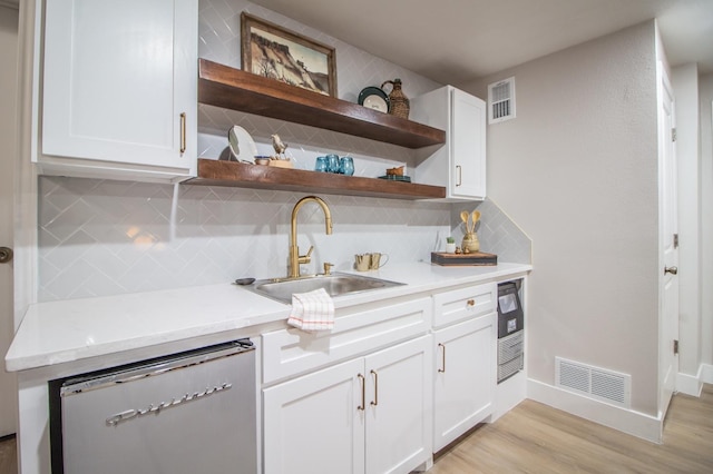 kitchen featuring sink, dishwasher, white cabinets, and light wood-type flooring