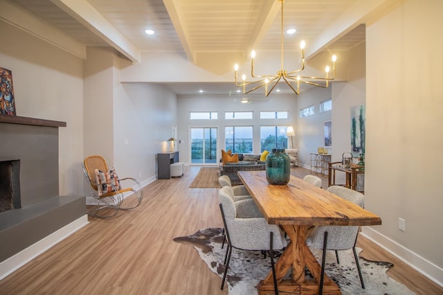 dining space featuring a chandelier, beam ceiling, and light hardwood / wood-style flooring