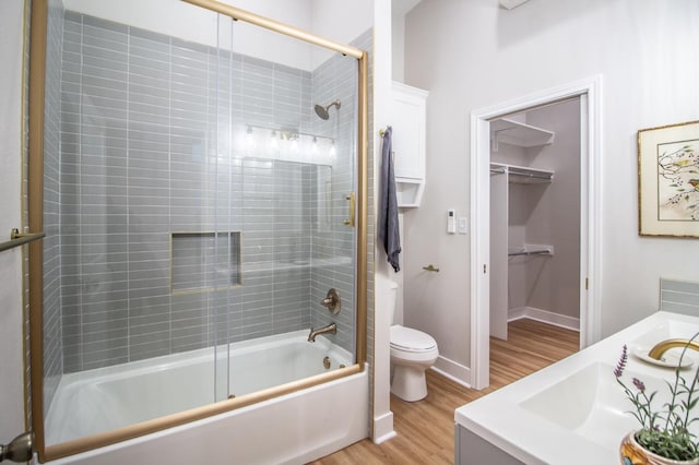 full bathroom with enclosed tub / shower combo, vanity, hardwood / wood-style flooring, and toilet