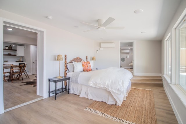 bedroom featuring a wall unit AC, light hardwood / wood-style floors, and ceiling fan