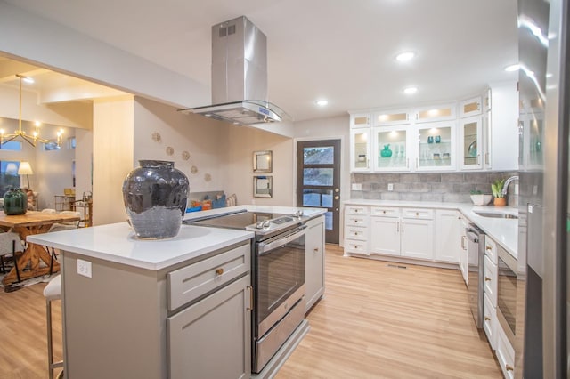 kitchen featuring a breakfast bar, white cabinetry, tasteful backsplash, island range hood, and appliances with stainless steel finishes