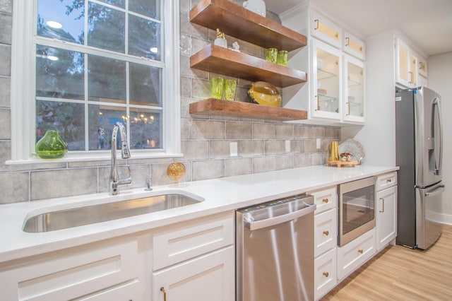 kitchen featuring sink, backsplash, white cabinets, light hardwood / wood-style floors, and stainless steel appliances