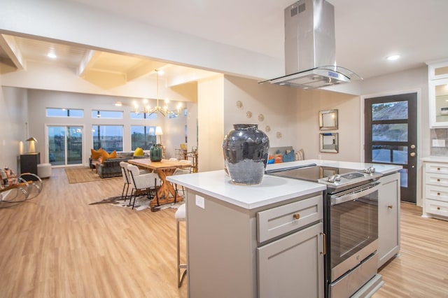 kitchen featuring light hardwood / wood-style flooring, a breakfast bar, island range hood, a kitchen island, and stainless steel electric stove