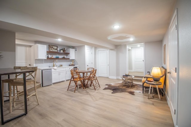 interior space featuring white cabinetry, stainless steel dishwasher, sink, and light wood-type flooring