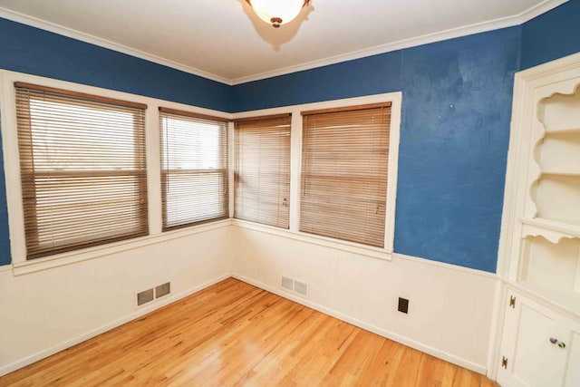 unfurnished room with ornamental molding and light wood-type flooring