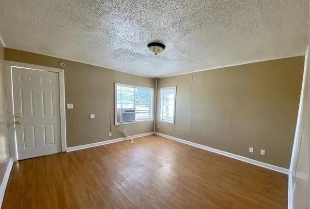 spare room featuring cooling unit, wood-type flooring, and a textured ceiling