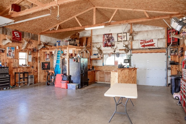 garage with black refrigerator with ice dispenser and a workshop area