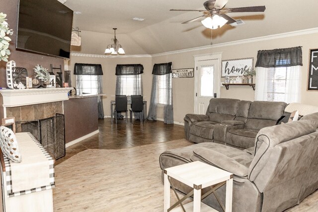 living room featuring lofted ceiling, a tile fireplace, a wealth of natural light, ceiling fan with notable chandelier, and tile patterned floors