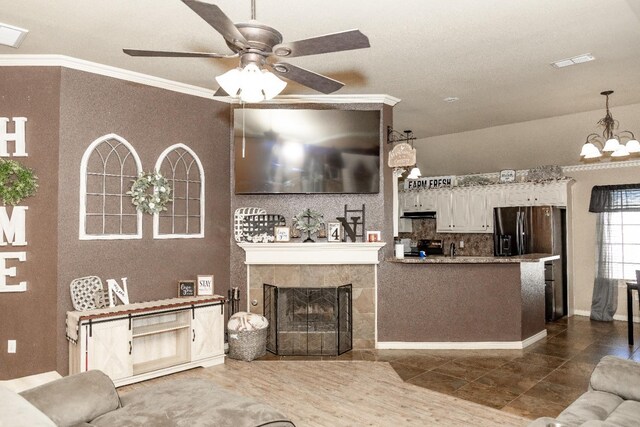 interior space featuring ornamental molding, a tiled fireplace, and ceiling fan with notable chandelier