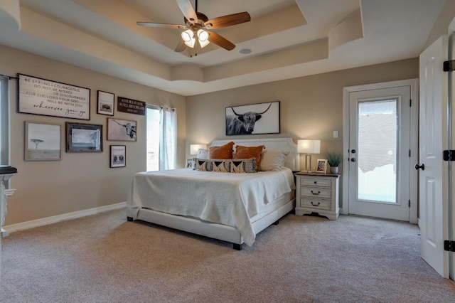 carpeted bedroom with multiple windows, access to exterior, and a raised ceiling