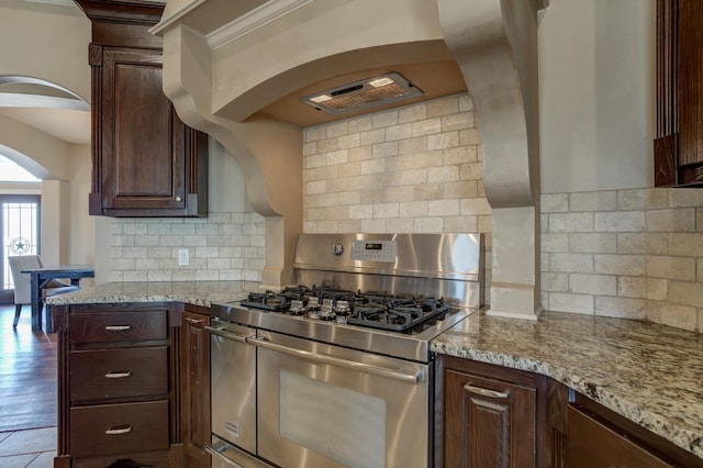 kitchen with wood-type flooring, backsplash, double oven range, dark brown cabinetry, and light stone countertops