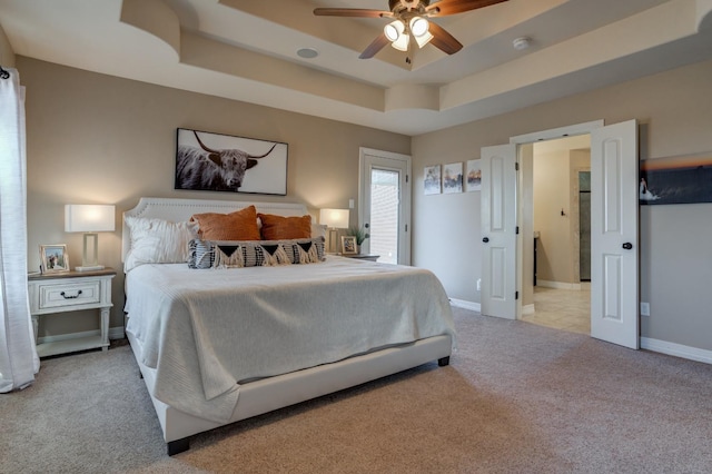 carpeted bedroom featuring ceiling fan and a raised ceiling