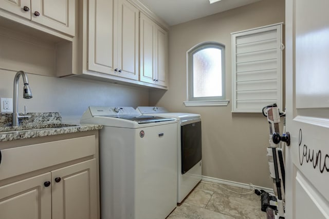 washroom with cabinets, washer and clothes dryer, and sink