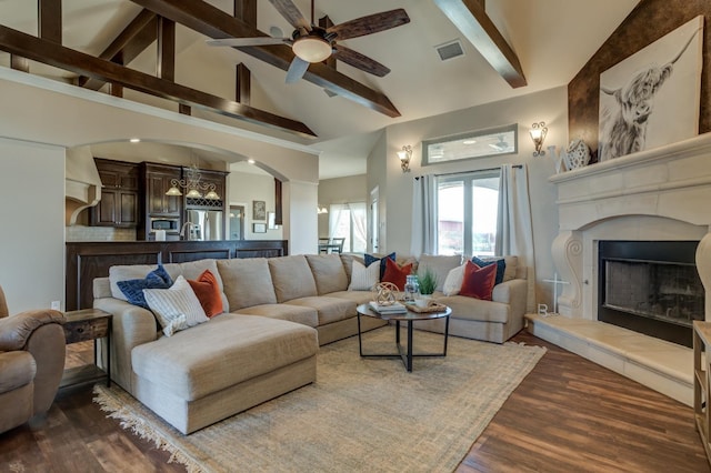 living room with ceiling fan, beam ceiling, high vaulted ceiling, dark hardwood / wood-style floors, and a tiled fireplace