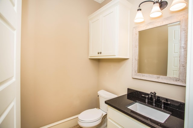 half bathroom featuring toilet, baseboards, and vanity