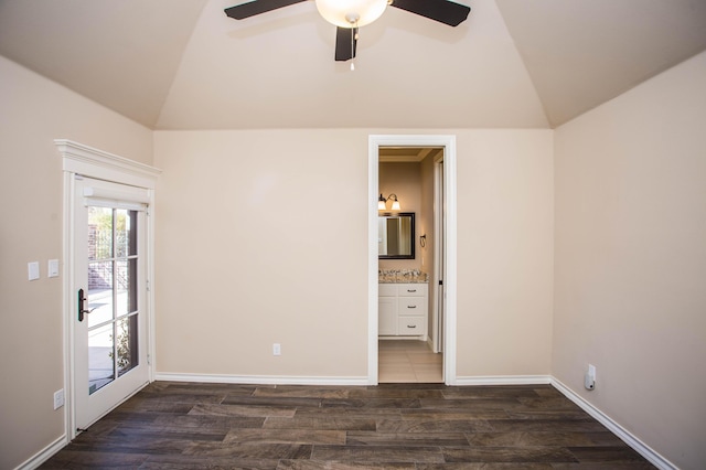 empty room featuring dark wood-style floors, lofted ceiling, baseboards, and a ceiling fan