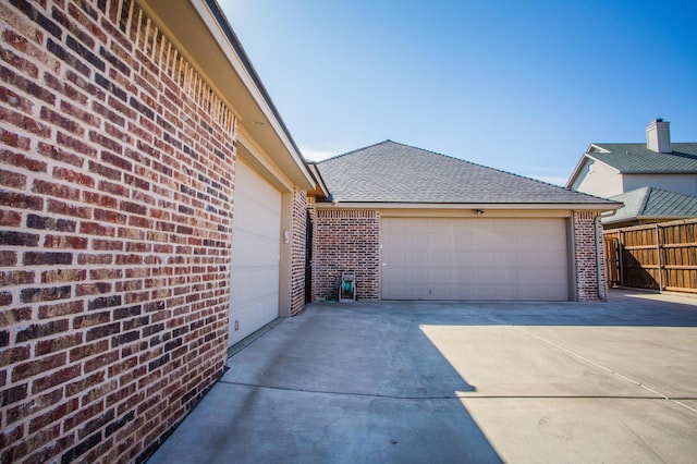 garage featuring fence and concrete driveway