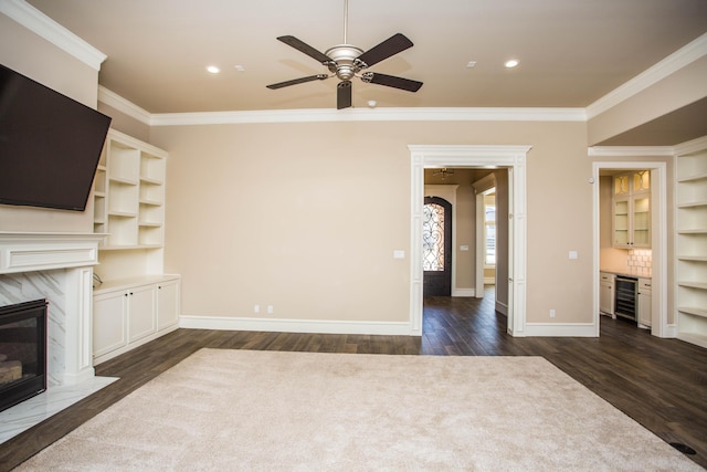 unfurnished living room featuring beverage cooler, a premium fireplace, baseboards, and crown molding