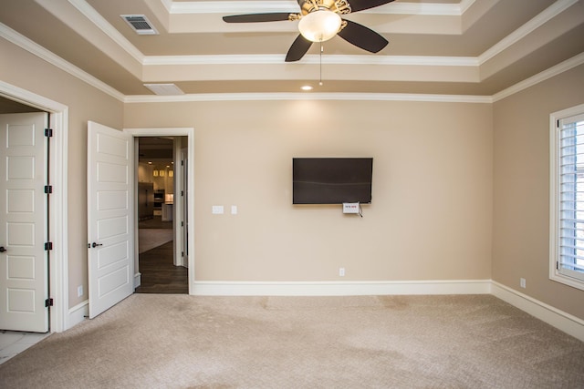 interior space with carpet flooring, visible vents, baseboards, ornamental molding, and a raised ceiling