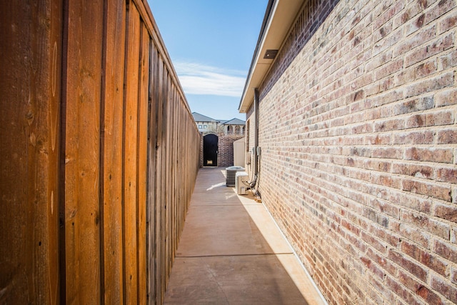 view of home's exterior with cooling unit, brick siding, a patio, and fence