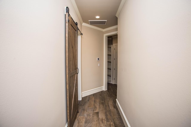 hallway with a barn door, visible vents, baseboards, dark wood-style floors, and crown molding