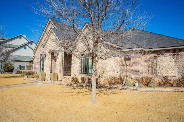 view of front facade with a front yard, stone siding, and brick siding