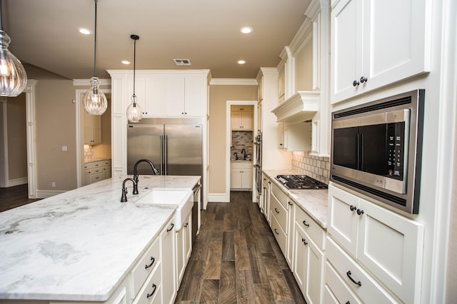 kitchen with pendant lighting, a large island, tasteful backsplash, white cabinetry, and built in appliances