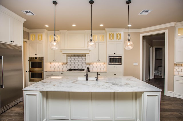 kitchen with glass insert cabinets, a large island with sink, a sink, and built in appliances