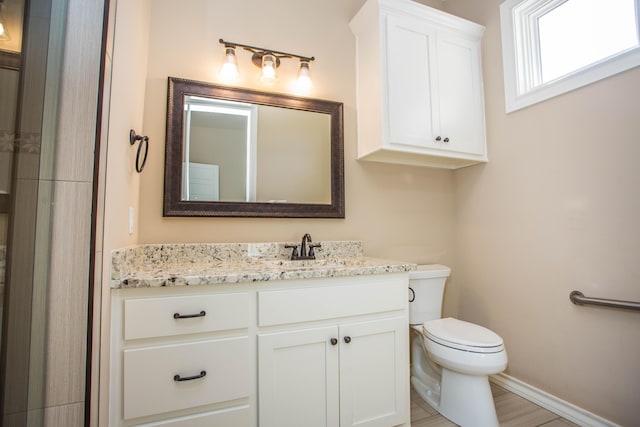 full bathroom with baseboards, vanity, and toilet