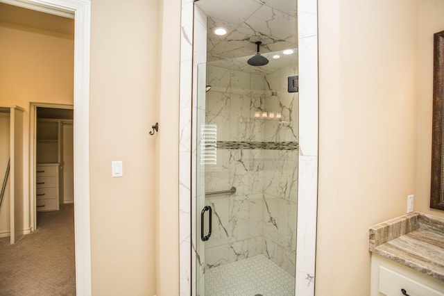 bathroom with a marble finish shower and vanity