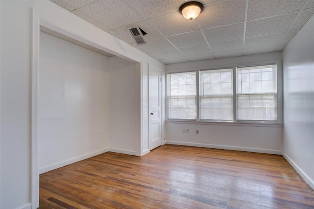 spare room featuring a drop ceiling and hardwood / wood-style flooring