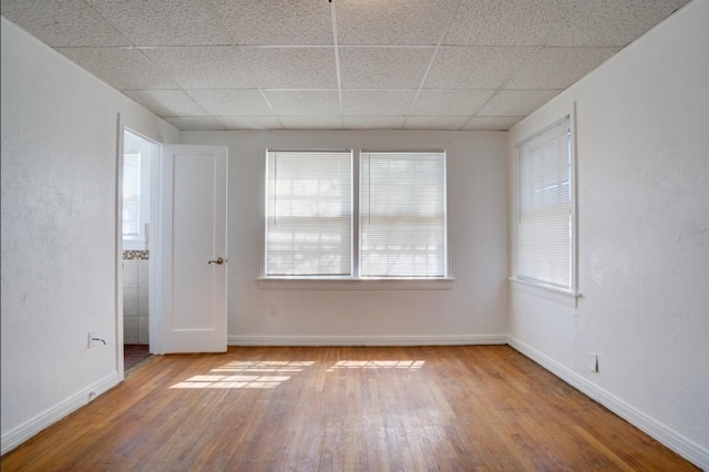 unfurnished room with a paneled ceiling and hardwood / wood-style floors