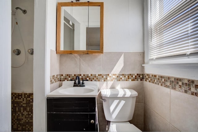 bathroom featuring vanity, tile walls, and toilet