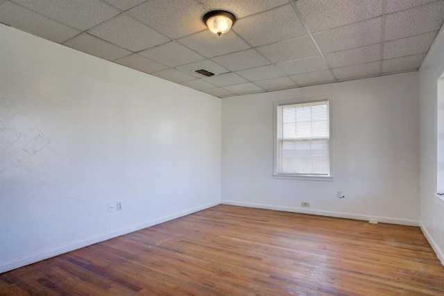 empty room with hardwood / wood-style flooring and a paneled ceiling