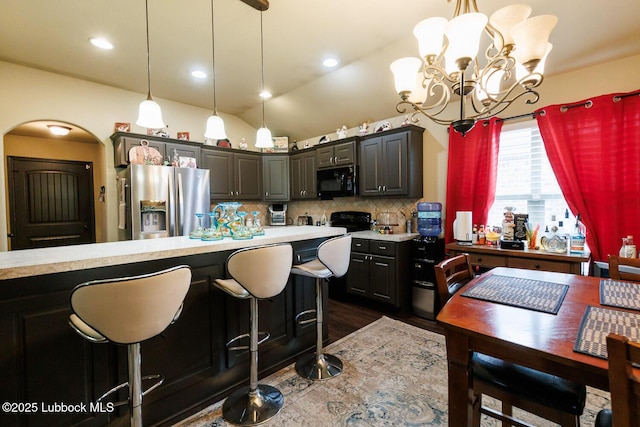 10018 Ave X, Lubbock, TX 79423 - kitchen featuring stainless steel refrigerator with ice dispenser, black microwave, light countertops, decorative backsplash, and a chandelier