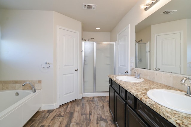 bathroom featuring vanity, wood-type flooring, and shower with separate bathtub