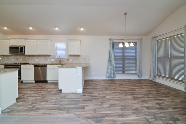 kitchen with stainless steel appliances, white cabinetry, light stone countertops, and pendant lighting