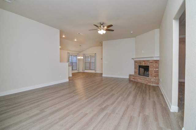 unfurnished living room with ceiling fan, lofted ceiling, light hardwood / wood-style floors, and a brick fireplace