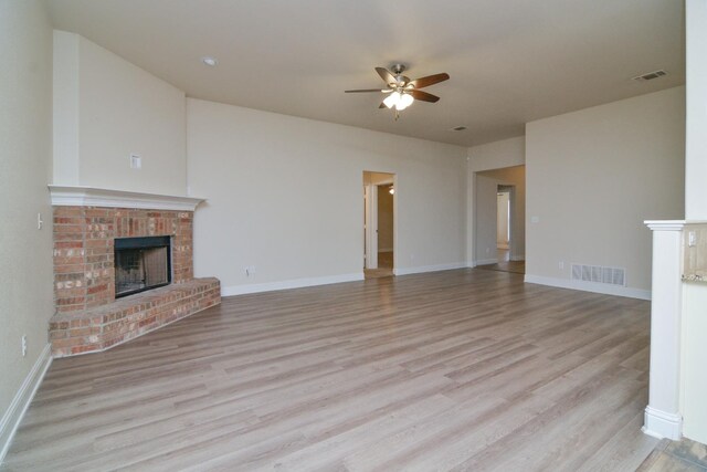 unfurnished living room featuring a fireplace, light hardwood / wood-style floors, and ceiling fan