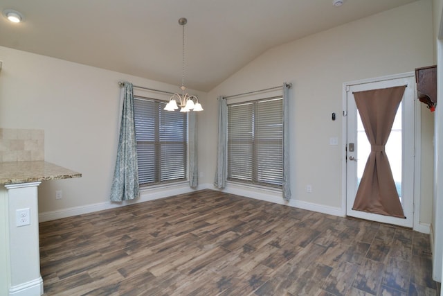 unfurnished dining area featuring lofted ceiling, dark wood-type flooring, and an inviting chandelier